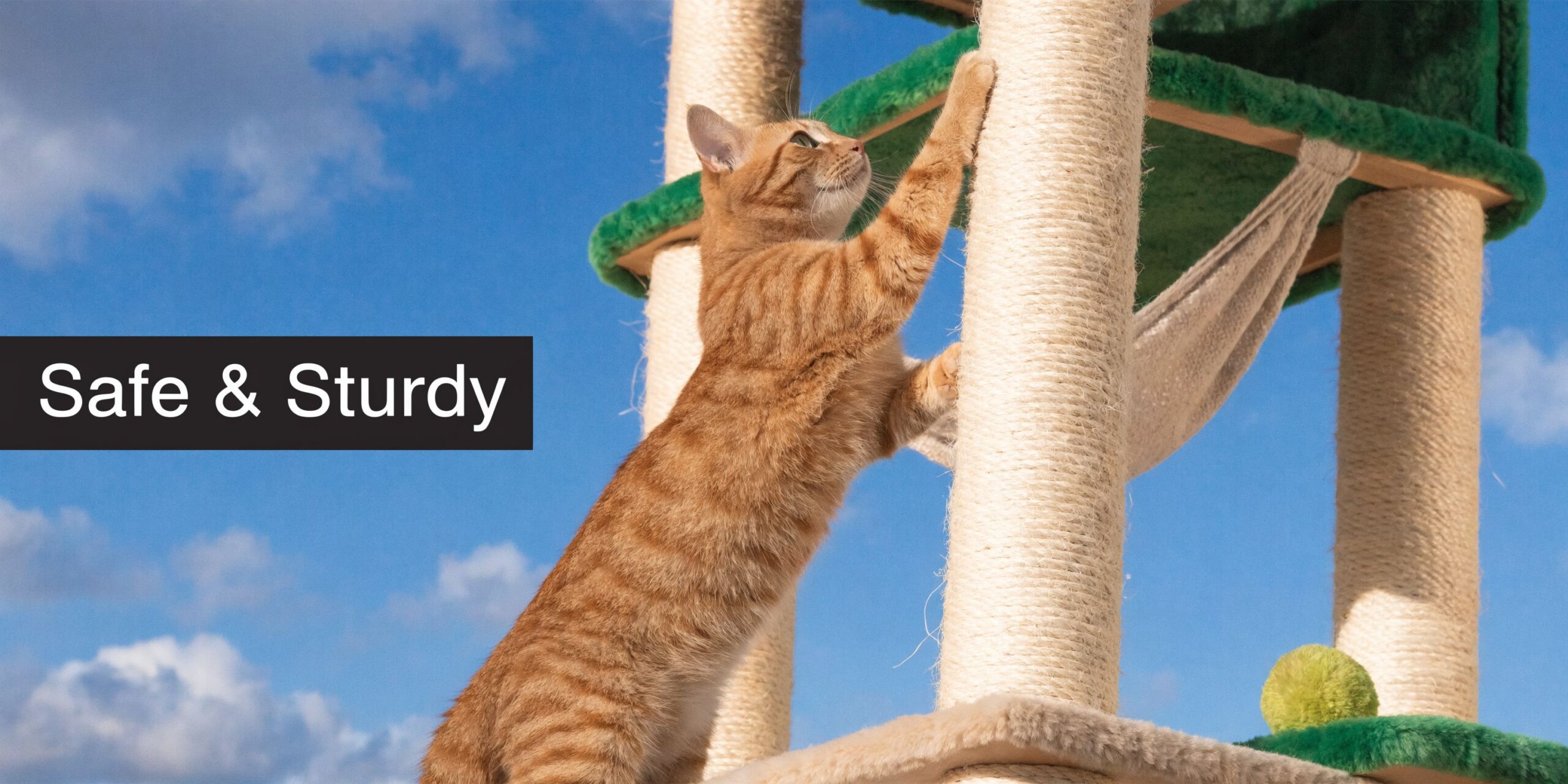 Een oranje cyperkat krabt aan een stevige krabpaal met een hangmat tegen een blauwe lucht met wolken.