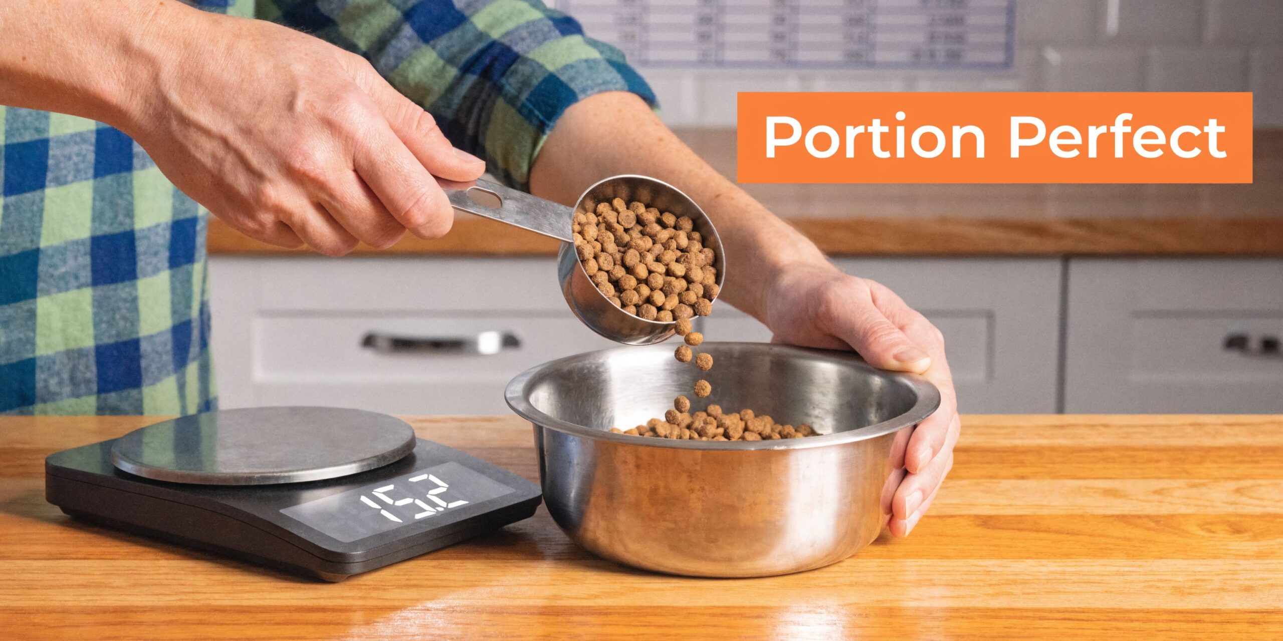 Een persoon weegt de portie droge hondenbrokken af met een metalen maatbeker en een keukenweegschaal in een keuken.