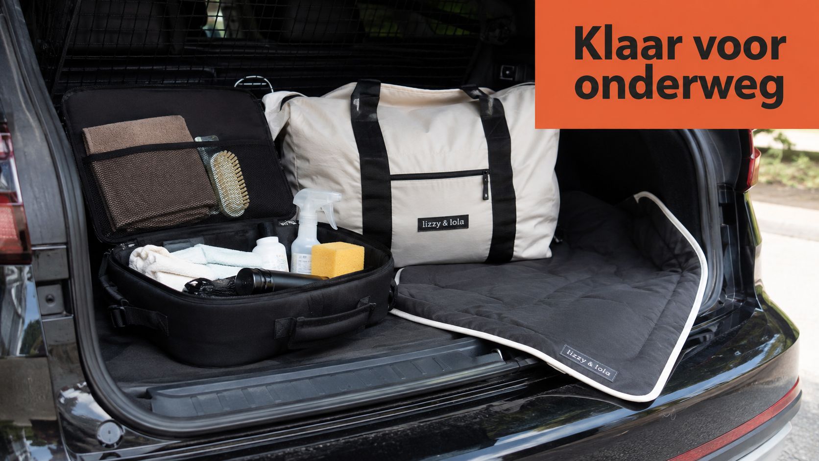 Een geopende tas met verzorgingsproducten voor honden en een ligmat in de kofferbak van een auto.